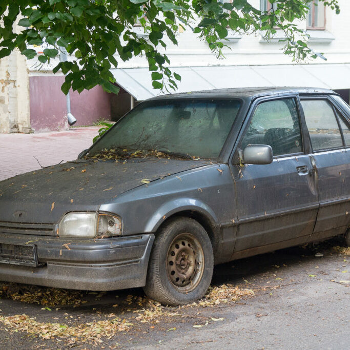 Rusty abandoned car on a city street